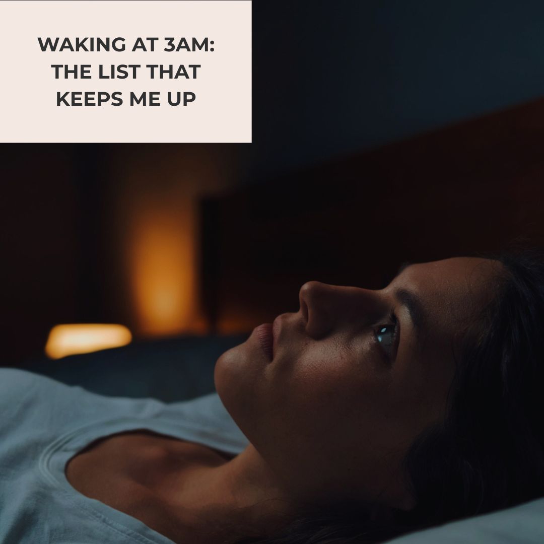 A woman with dark hair lies awake in bed in a dark bedroom, eyes open, in a post about waking at 3AM in menopause.
